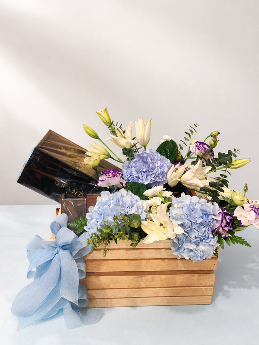 Blue hydrangea, white lily and chocolate gift crate by James Flowers Mumbai