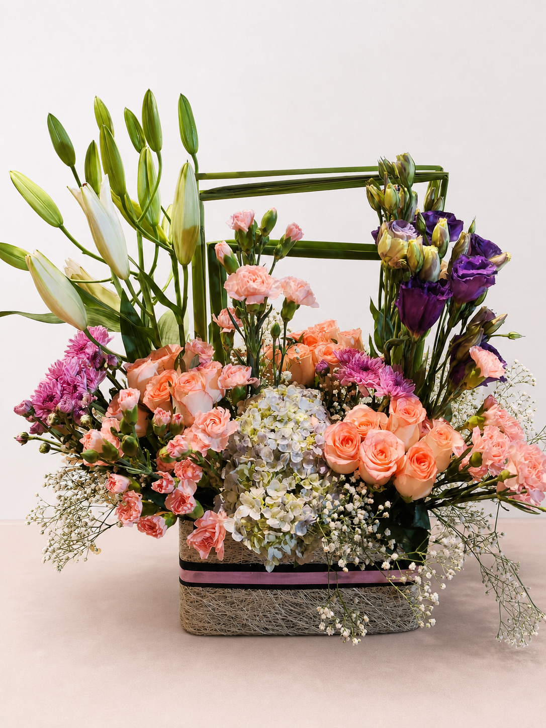 Peach roses, white lilies and purple lisianthus luxury flower basket by James Flowers Mumbai
