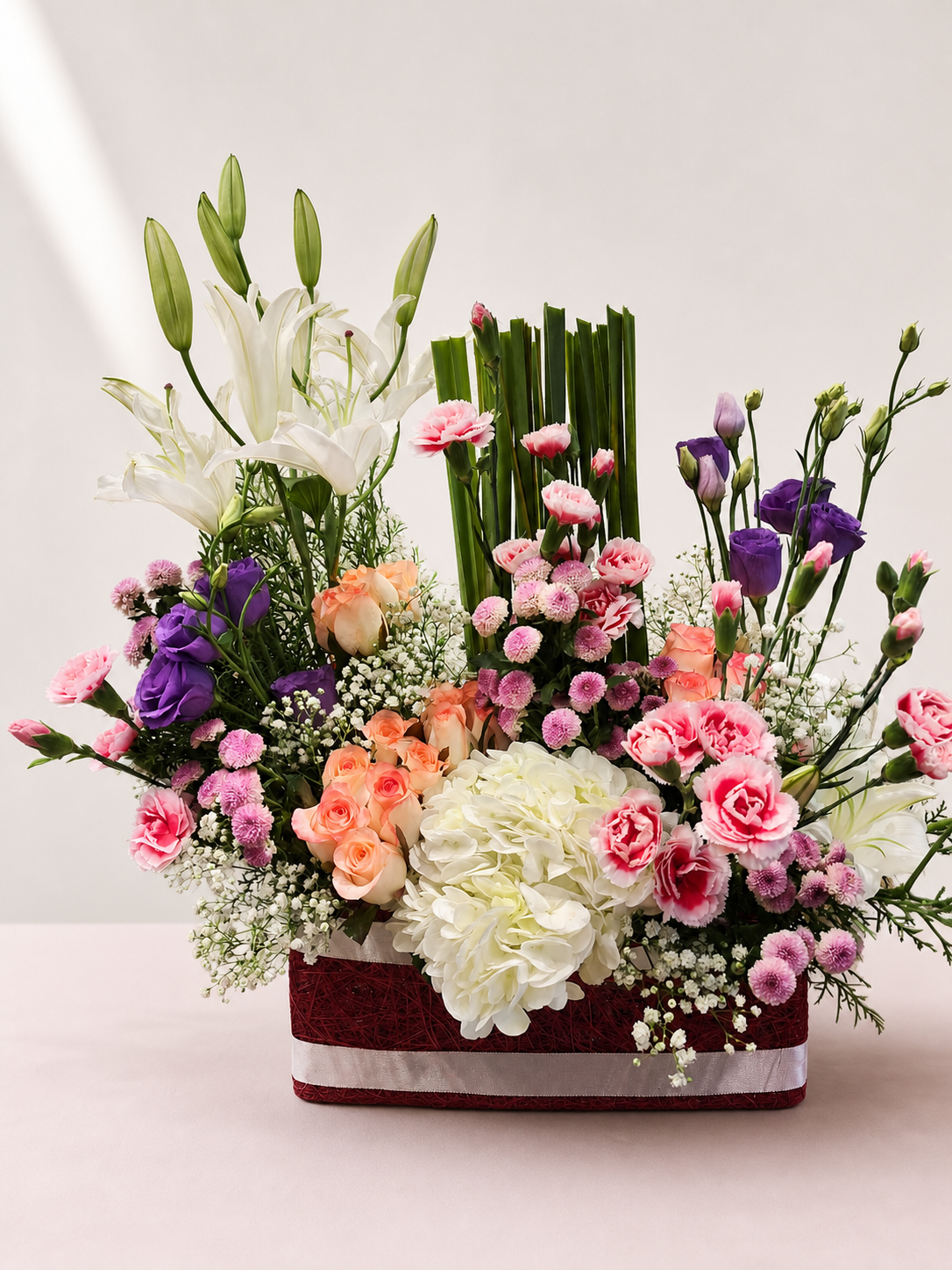 Pink lily, peach rose and hydrangea luxury flower basket by James Flowers Mumbai